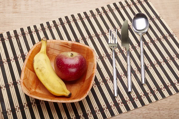 Bowl with banana and strawberry and cutlery on the table — Stock Photo, Image