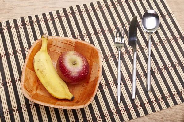 Bowl with banana and strawberry and cutlery on the table — Stock Photo, Image