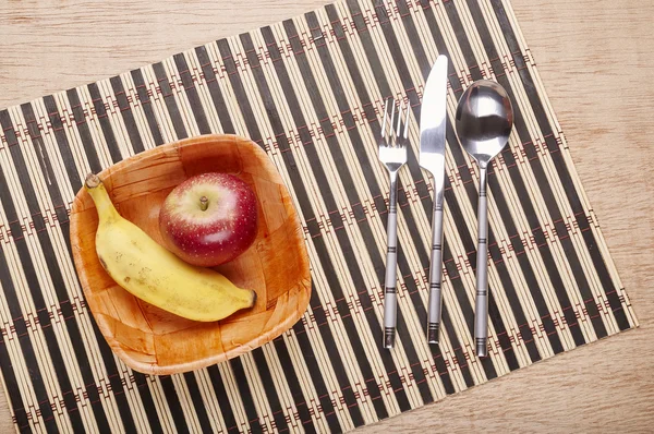 Bowl with banana and strawberry and cutlery on the table — Stock Photo, Image