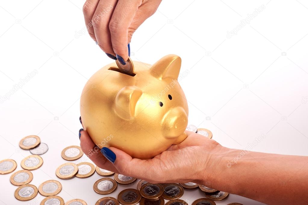 Woman's hand putting coins  Brazilian money into piggy bank