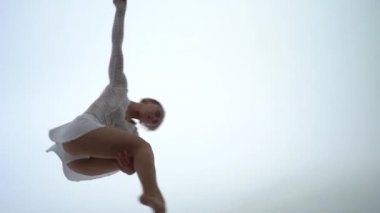 Kadın hava kayışları sanatçısı yavaş çekimde beyaz arka planda performans sergiliyor. Arzu, zarafet ve zarafet kavramı 