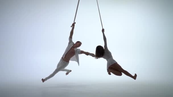 Aerial straps duo wearing white costume on white background doing performance in slow motion. Concept of desire, attraction and relationship — Stock Video