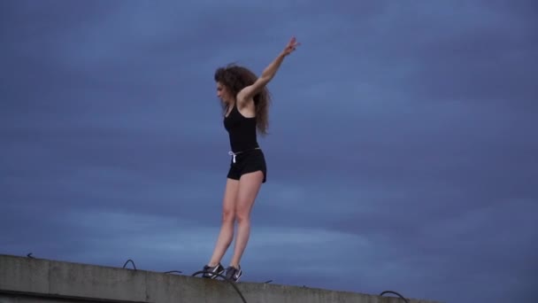 Mujer súper flexible saltando en cámara lenta sobre el dramático fondo del cielo. Concepto de sueño y fuerza de voluntad — Vídeo de stock