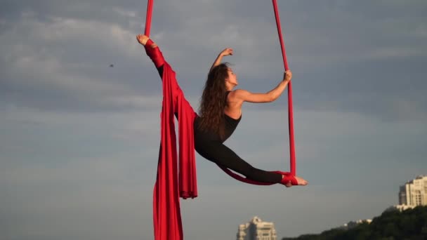 Kadın sirk sanatçısı esnekliğini gösteriyor ve arka planda kırmızı havadan ipekle ikiye ayrılıyor. Sağlıklı yaşam tarzı kavramı — Stok video
