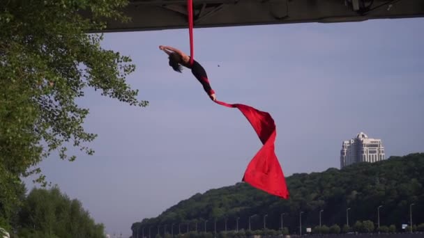 Acrobata feminino flexível fazendo truque louco e perigoso com seda aérea vermelha no fundo do céu é câmera lenta. Conceito de desejo e paixão — Vídeo de Stock