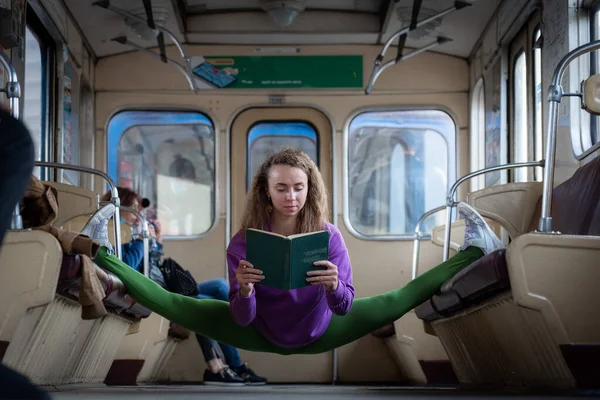 女孩坐在地铁车厢的隔板上看书。教育和自我发展的概念. — 图库照片