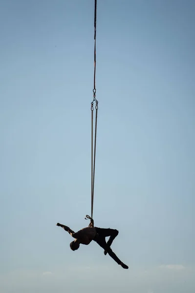 Silueta de artista de circo en las correas aéreas sobre fondo azul cielo. Concepto de fuerza de voluntad, motivación y estilo de vida saludable — Foto de Stock