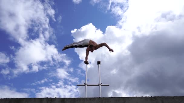 Flexible male circus Artist keep balance by one hand on the rooftop against amazing cloudscape. Willpower, potential and desire concept — Stock Video