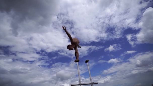 Circo masculino flexível Artista manter o equilíbrio por uma mão no telhado contra a incrível paisagem nublada. Motivação, paixão e conceito de realização — Vídeo de Stock