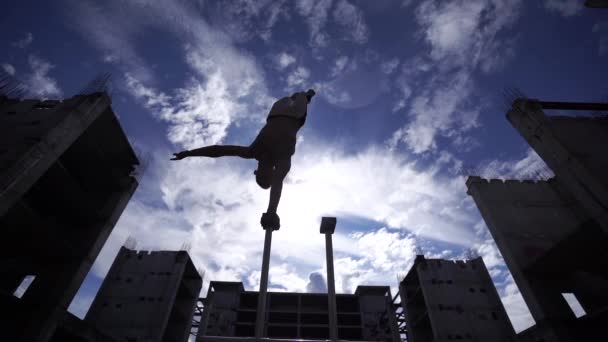 Elastyczny cyrk męski Artysta zachować równowagę jedną ręką z niesamowitym chmurowym krajobrazem i nowoczesnych konstrukcji. Indywidualność, kreatywność i współczesny punkt widzenia — Wideo stockowe