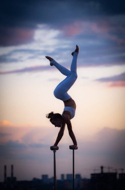 Esnek kadın sirk Artis dengeyi sağlar ve dramatik günbatımına ve şehir manzarasına karşı çatıda kıvrılır. Motivasyon, tutku ve başarı kavramı 