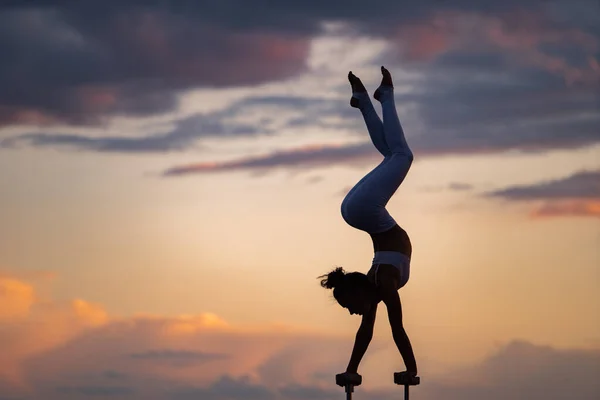 Silueta de chica flexible y en forma haciendo handstand y manteniendo el equilibrio contra el dramático desajuste. Concepto de yoga y estilo de vida saludable — Foto de Stock