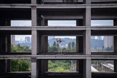 Esnek erkek sirk sanatçısı bir eliyle gökyüzü arka planındaki beton yapının dengesini koruyor. Suda yansıması var. Eşitlik, tutarlılık ve simetri kavramı.