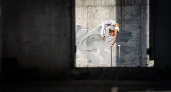Chica flexible y en forma de pie sobre sus manos manteniendo el equilibrio en el edificio abandonado. Concepto de esfuerzo y estilo de vida saludable — Foto de Stock