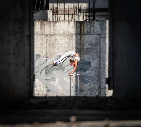 Chica flexible y en forma de pie sobre sus manos manteniendo el equilibrio en el edificio abandonado. Concepto de esfuerzo y estilo de vida saludable — Foto de Stock