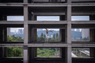 Esnek erkek sirk sanatçısı beton yapıda bir elle dengesini koruyor. Bireysellik, olağanüstü ve özgünlük.