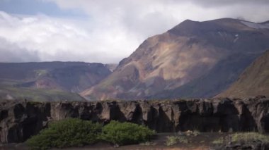 Volkanik manzarayla çevrili dağlardan geçen bulutlar. İzlanda doğası