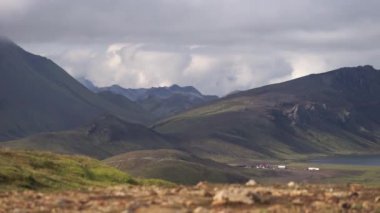 Hvanngil dağ kulübesi ve yeşil tepeli kamp alanı, nehir deresi ve göl manzaralı. Laugavegur yürüyüş yolu, İzlanda