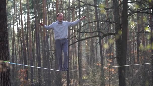 Man springen en doen trucs op slackline in het bos in slow motion — Stockvideo