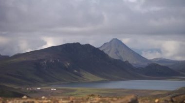 Hvanngil dağ kulübesi ve yeşil tepeli kamp alanı, nehir deresi ve göl manzaralı. Laugavegur yürüyüş yolu, İzlanda