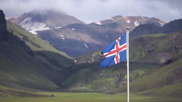 Bandera de Islandia sobre el fondo de montañas verdes y cielo azul — Vídeos de Stock