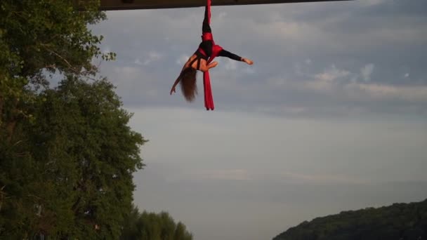 Elastyczna akrobatka wykonująca szalone i niebezpieczne triki z czerwonym powietrznym jedwabiem na tle nieba. Pojęcie pożądania i namiętności — Wideo stockowe