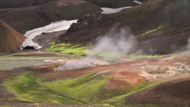 Randonneur flou passant par un paysage actif volcanique avec grenouille, glacier, collines et mousse verte sur le sentier Fimmvorduhals près de Landmannalaugar de la journée ensoleillée d'été, Islande — Video