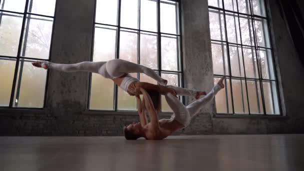 Acrobatic duet robi ładną pozę na tle ogromnych okien z jesiennymi drzewami pomarańczowymi na zewnątrz. Pojęcie relacji, szczęścia i zaufania — Wideo stockowe