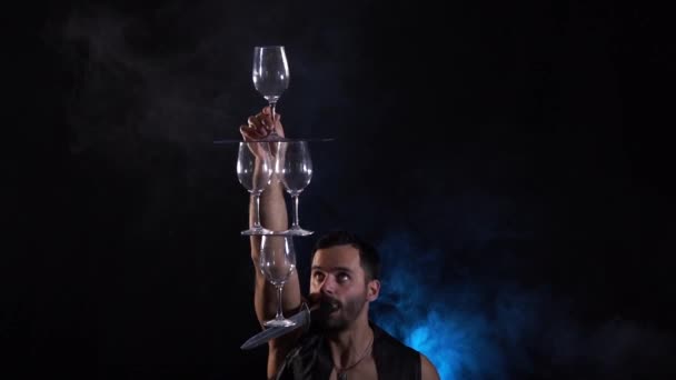 Man hold knife in the mouth and keep in balance wineglasses on it. concentration — Stock Video