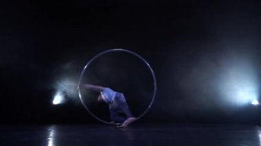 Kaslı Sirk sanatçısı yavaş çekimde bir Cyr çarkında dönüyor. Hareket, hareket ve denge kavramı