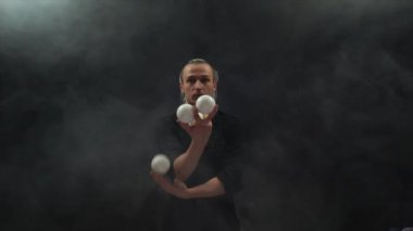 Siyah giyen adam beyaz toplarla hokkabazlık yapıyor. Konsantrasyon, kontrol ve yetenek.