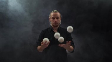 Siyah giyen adam beyaz toplarla hokkabazlık yapıyor. Konsantrasyon, kontrol ve yetenek.