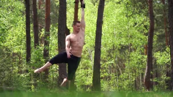 Cirkus artist gör calisthenics i den gröna parken med antenn remmar. — Stockvideo