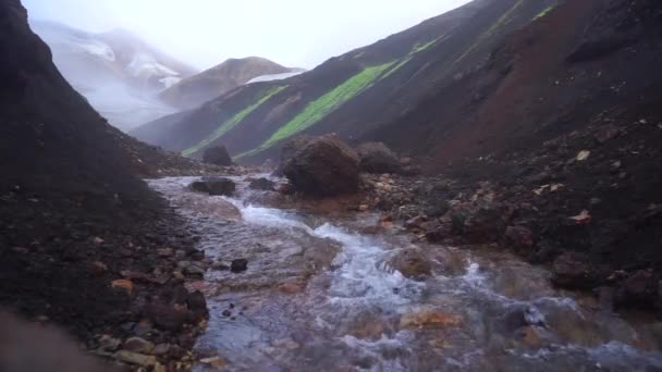 Μαγευτικό τοπίο με κομμάτι παγετώνα, πολύχρωμη γεωλογική δομή και μικροσκοπικό ποτάμι που περνά σε αργή κίνηση. Διαδρομή πεζοπορίας Laugavegur, Ισλανδία — Αρχείο Βίντεο