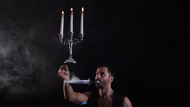 입에 칼을 쥐고 있는 서커스 미술가가 촛대로 풍선을 불어서 균형을 유지하고 있는 모습 — 비디오