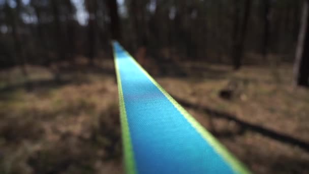 Homem pulando e fazendo truques em slackline na floresta em câmera lenta — Vídeo de Stock