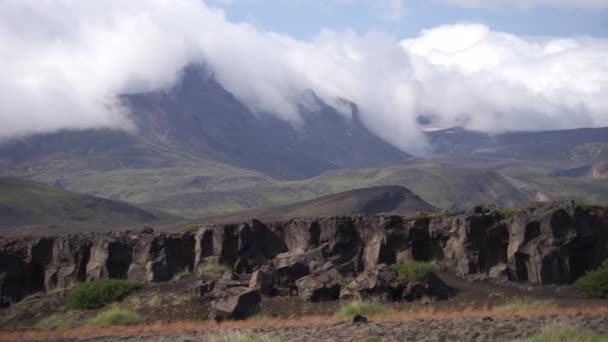 Pilvet kulkevat vuorten huipulla vulkaanisen maiseman ympäröimänä. Islannin luonto — kuvapankkivideo