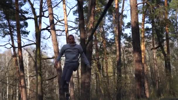 Omul sărind și făcând trucuri pe linia slackline în pădure în mișcare lentă — Videoclip de stoc