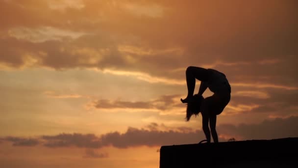 柔韧的女孩在夕阳西下时以慢镜头在空中倒立 — 图库视频影像