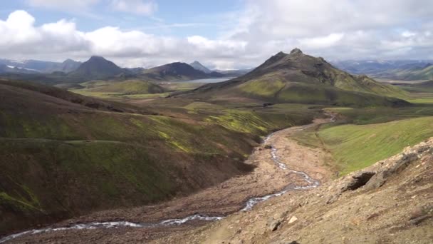 Widok na dolinę górską z zielonymi wzgórzami, strumień rzeczny i jezioro. Ścieżka turystyczna Laugavegur, Islandia — Wideo stockowe