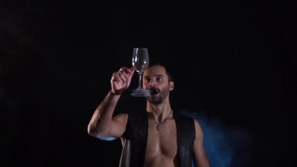 Een man houdt een mes in de mond en houdt er wijnglazen op. concentratie — Stockvideo