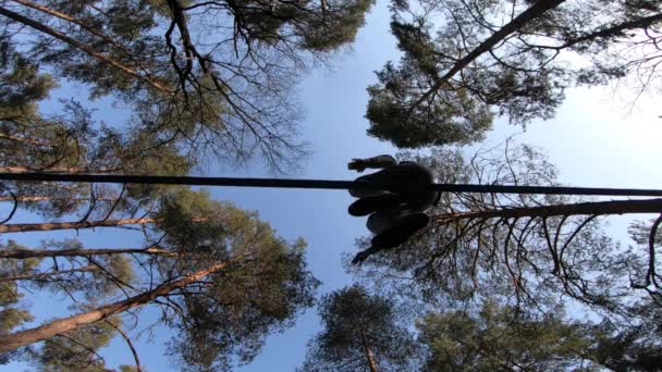 Человек прыгает и делает трюки на slackline в лесу в замедленной съемке — стоковое видео