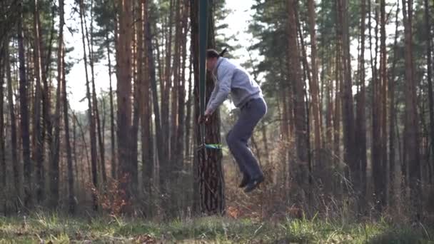 사람은 슬로우 모션으로 숲의 slackline 에서 점프 및 트릭을 수행 — 비디오