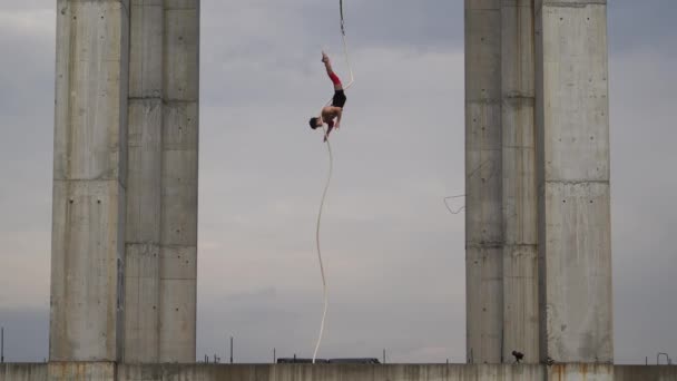 Artista de circo fuerte y musculoso actuando en la cuerda aérea al aire libre entre dos columnas de hormigón en el fondo del cielo, Concepto de coraje, control y resistencia — Vídeo de stock