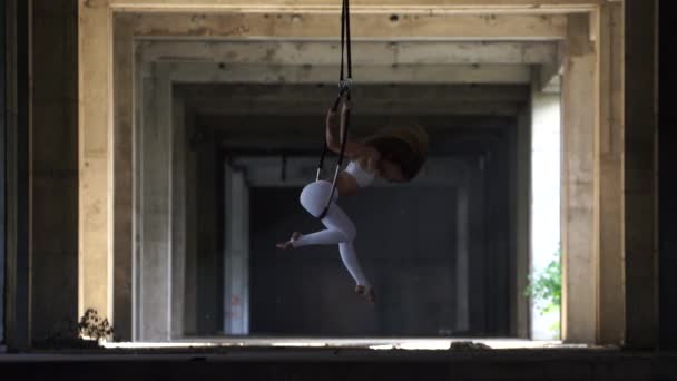 Гибкая и привлекательная артистка цирка, выступающая с воздушным обручем в заброшенном здании — стоковое видео