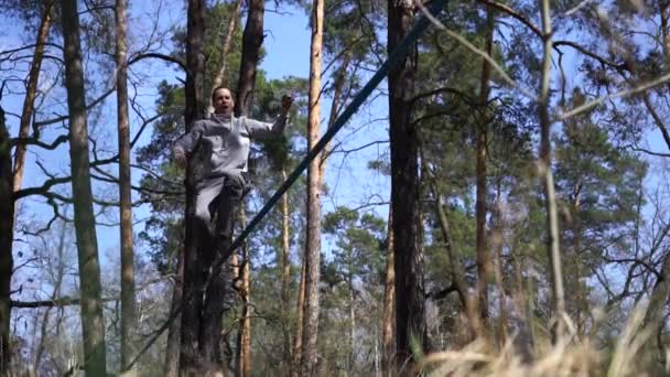 Man springen en doen trucs op slackline in het bos in slow motion — Stockvideo