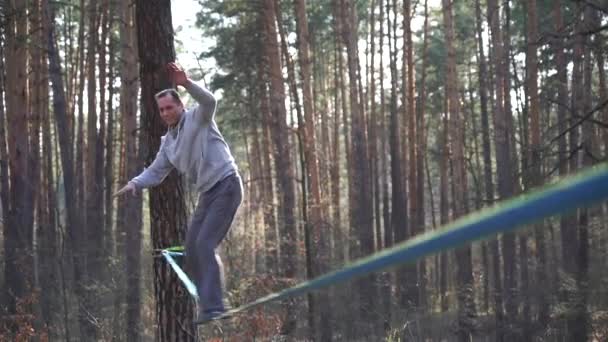 Man jumping and doing tricks on slackline in the forest in slow motion — Stock Video