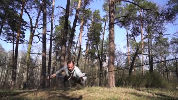 Man springen en doen trucs op slackline in het bos in slow motion — Stockvideo