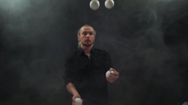 Siyah giyen adam beyaz toplarla hokkabazlık yapıyor. Konsantrasyon, kontrol ve yetenek.