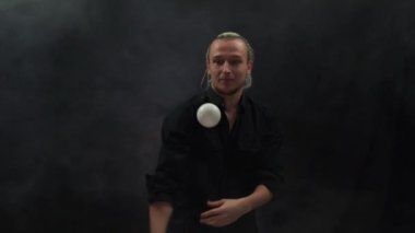 Siyah giyen adam beyaz toplarla hokkabazlık yapıyor. Konsantrasyon, yetenek, hız, tepki